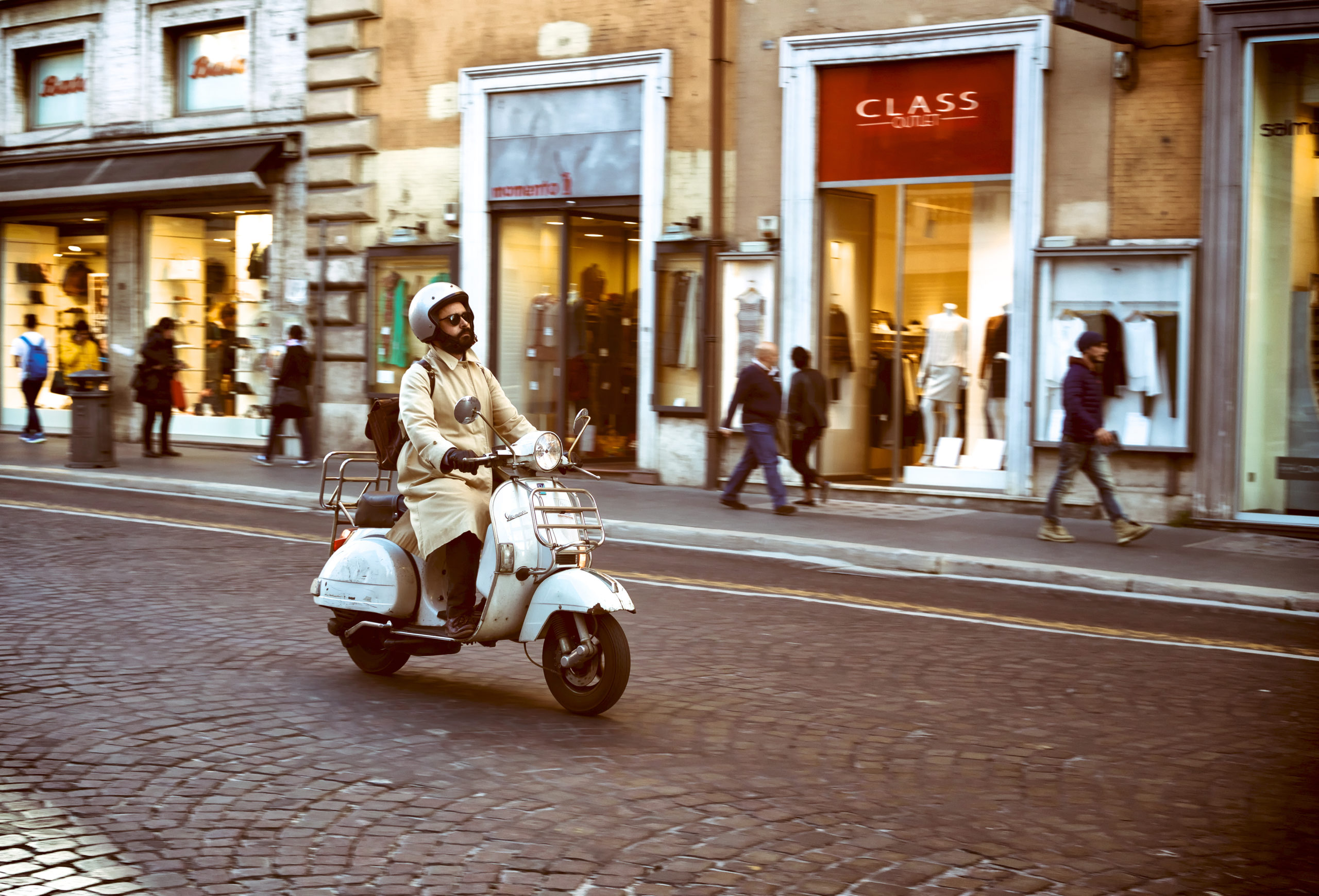 Ein Mann fährt mit einer alten Vespa durch die Straßen Roms.