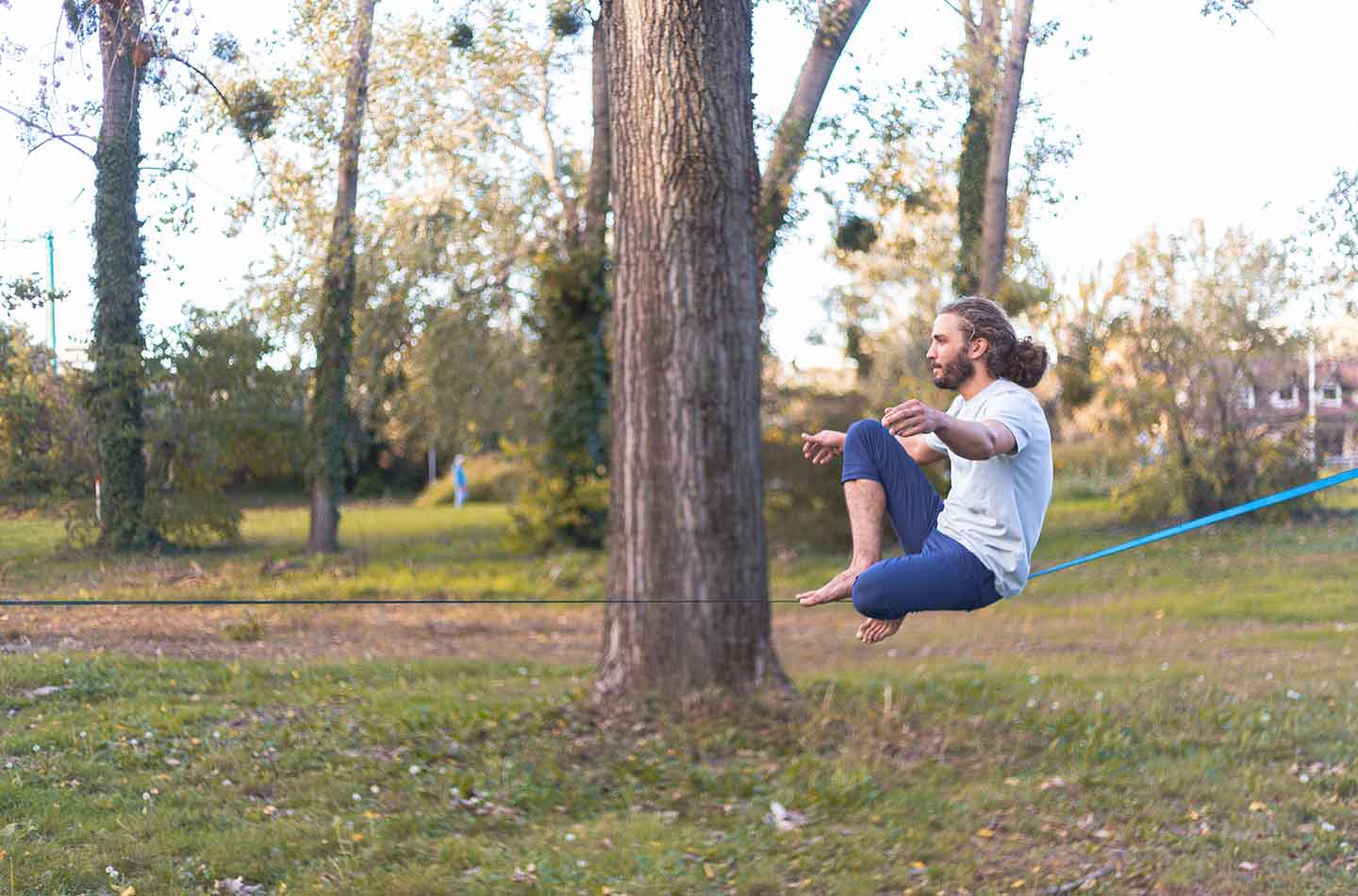 Slackliner auf einer Slackline im Park zwischen zwei Bäumen