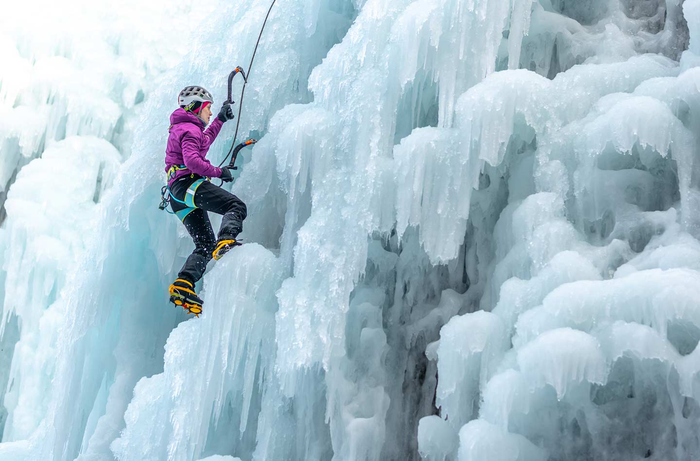 Eine Frau klettert an einem vereisten Wasserfall hoch