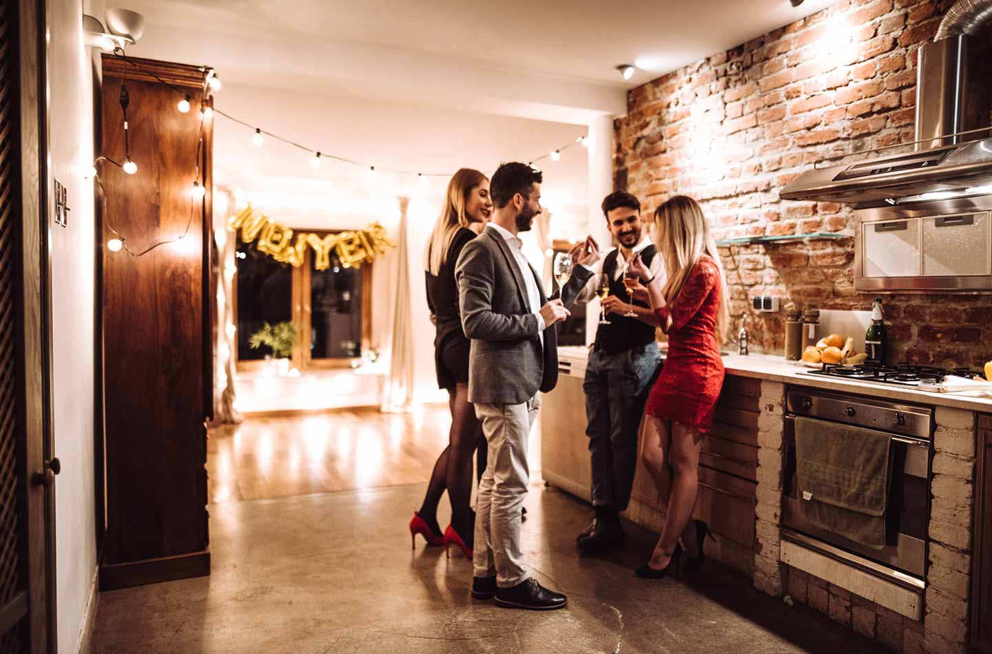 Vier Freunde in der Küche an Silvester stoßen mit Wein an
