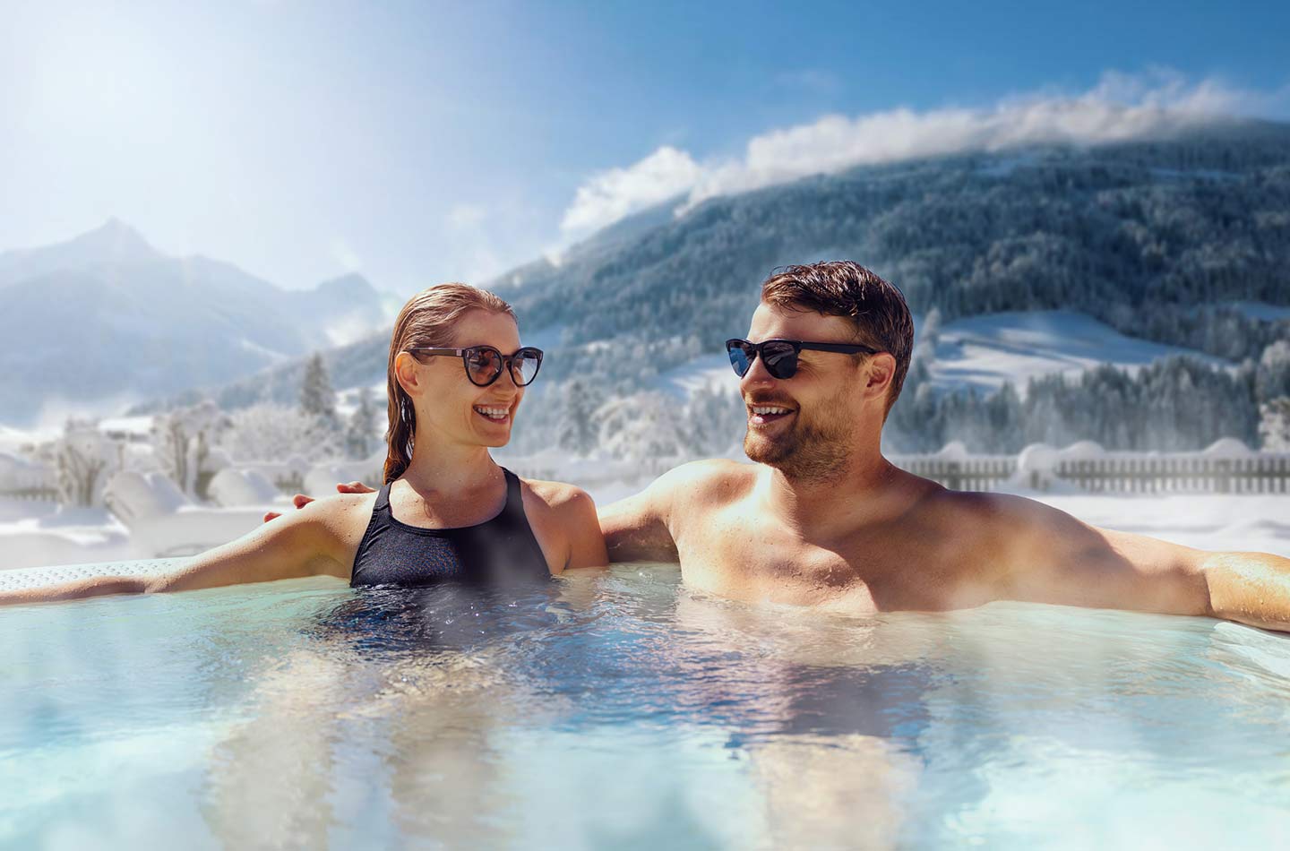 Paar im Whirlpool im Winter mit Bergen im Hintergrund