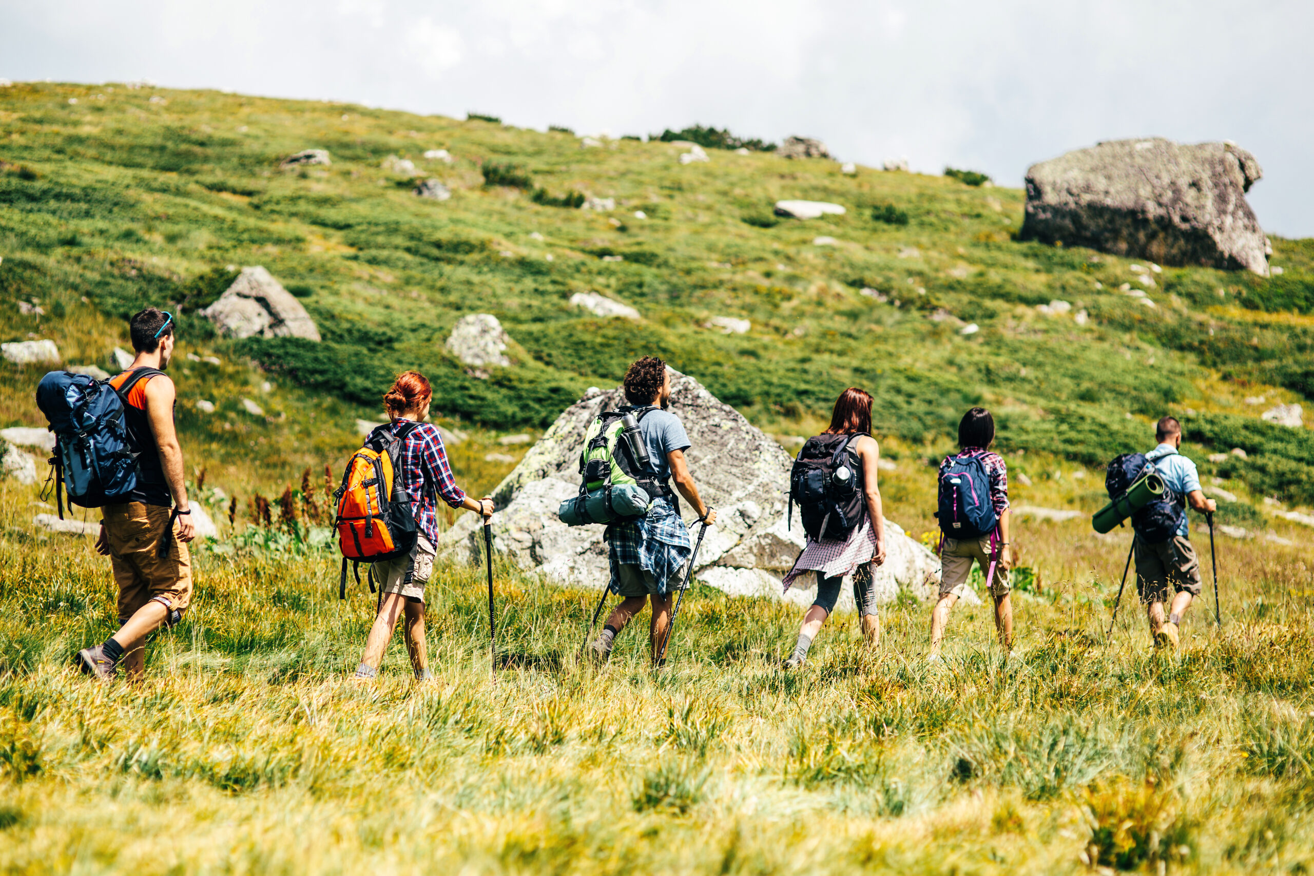 Frühling Wanderung mit Freunden durch grüne Hügel auf dem Weg zum Gipfel