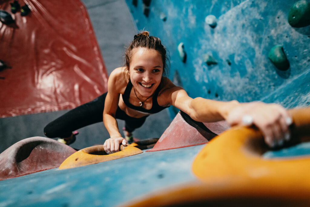 Junge Frau klettert in der Kletterhalle
