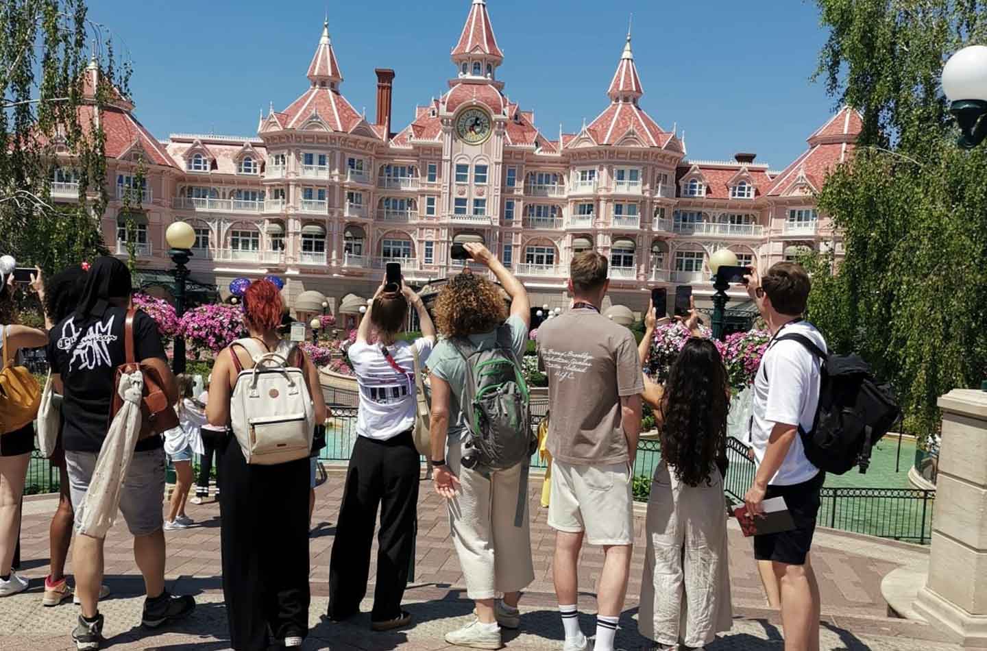Eine Gruppe von Leuten macht Bilder von dem Eingang des Disneyland Paris