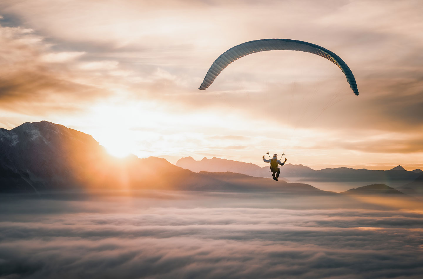 Fallschirmspringer schwebt über den Wolken bei Sonnenuntergang