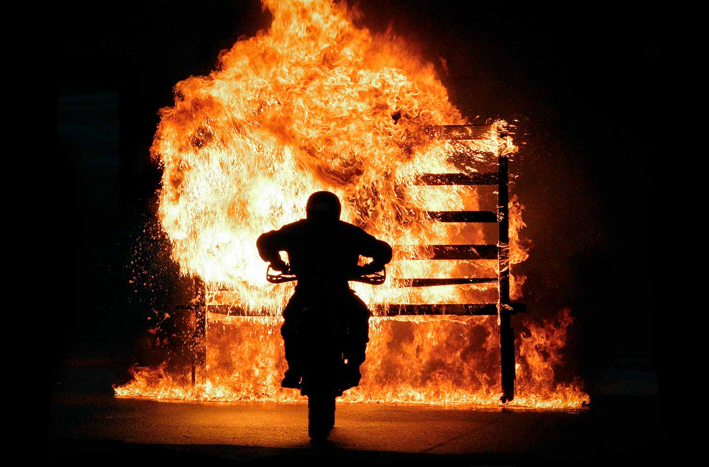 Ein Mann sitzt auf einem Motorrad und hinter ihm ist Feuer
