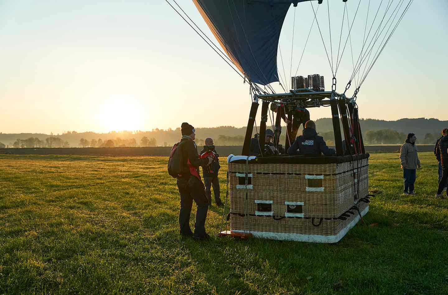 Der Heißluftballon steht auf dem Boden auf einer Wiese bei Sonnenaufgang